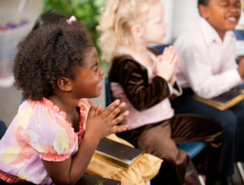 A group of multi-ethnic children at Sunday School in a real church classroom. Very shallow focus. Selective focus on girl closest to the camera